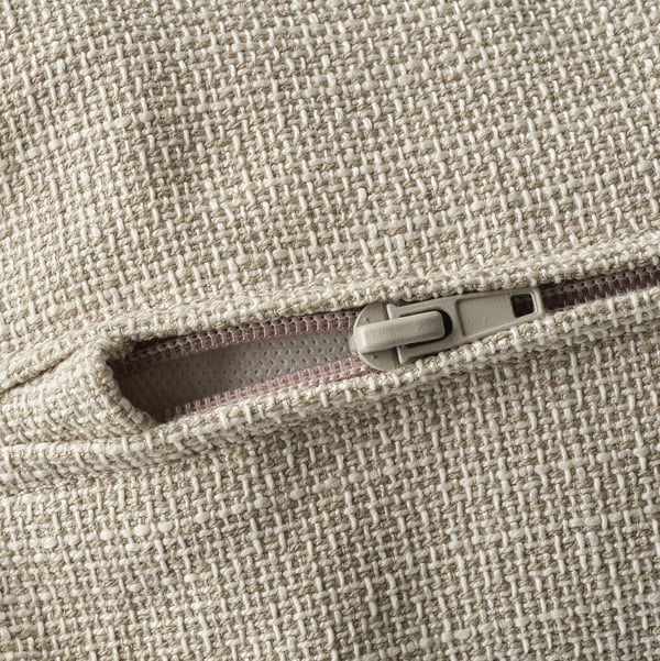 Nahaufnahme des Reißverschlusses auf einem beigen strukturierten Sofa, das Qualität und Designdetails zeigt.