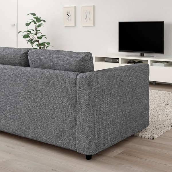 Modernes Wohnzimmer mit großem grauem VIMLE-Sofa an der Wand, Flachbildfernseher auf dem Sockel, Pflanze und Teppich; Minimalistisches Dekor.