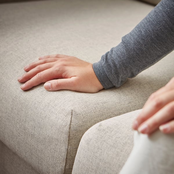 Das Bild zeigt die Hände, die auf dem VIMLE-Sofa ruhen. Graue Polsterung, weicher Stoff, L-förmiges Design.
