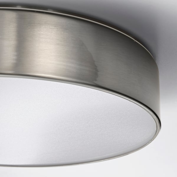 Nahaufnahme einer modernen Deckenleuchte aus gebürstetem Nickel mit glattem Metallfinish und mattiertem Acryl-Lichtdiffusor.