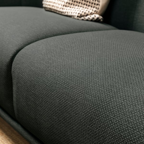 Dunkelgrünes Sofa aus strukturiertem Stoff, tiefe Sitzfläche, einladende Form.