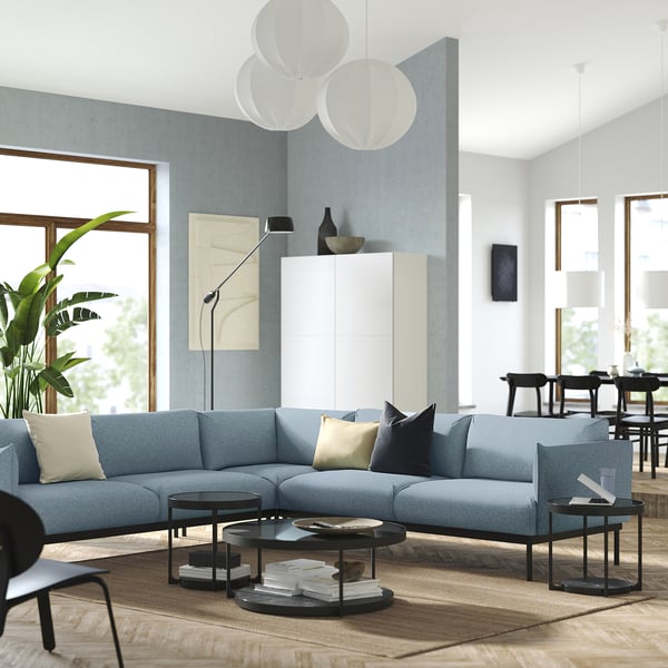 Modern living room with ÄPPLARYD blue sofa, round coffee table, large windows, and hanging lamps.