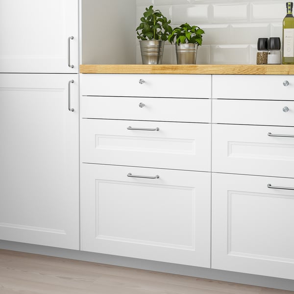 Modern white kitchen with AXSTAD cabinets and green plants.