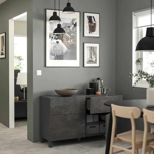 Modern kitchen with black and light wood furniture. Grey cabinets, hanging lamps, and printed art on green walls.