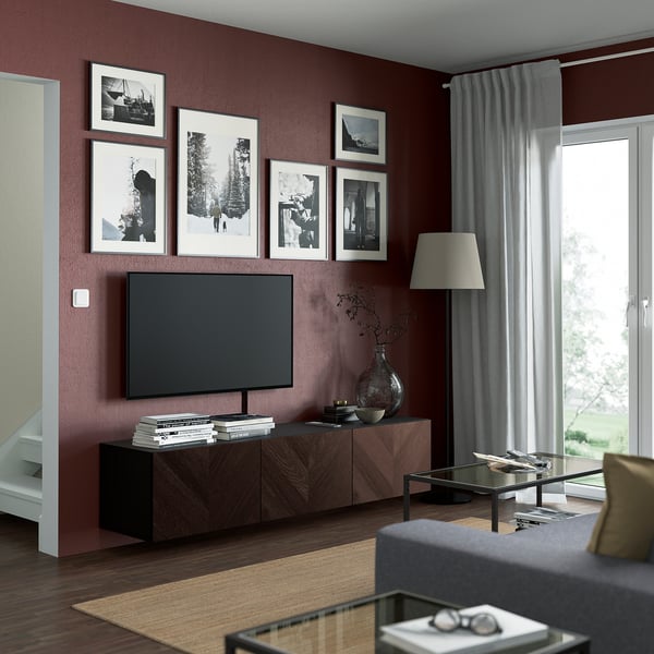 Modern living room with BESTÅ tv bench in dark wood, flat-screen tv, black frames, grey curtains, and glass coffee table.