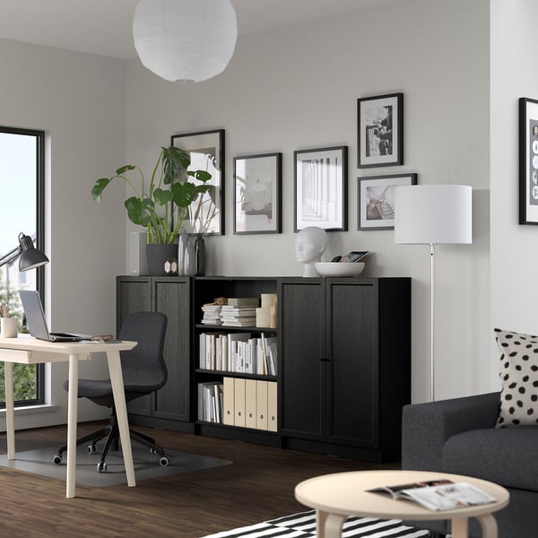 Modern home office with BILLY bookcase, desk, plant, art, sofa, and lamp.