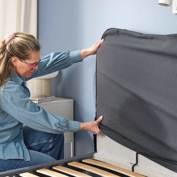 Person opens BLÅFJÄLLET ottoman bed, showing storage and lift mechanism.