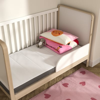 White baby mattress on wooden bed, with cute pillow and toy. Cosy and safe.