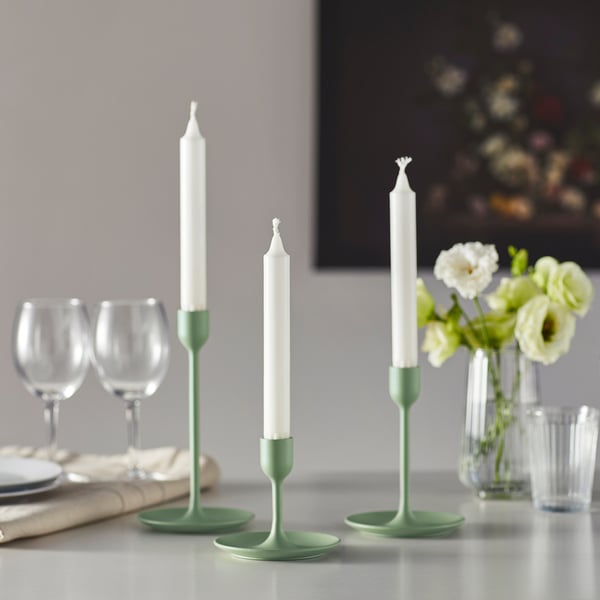 Green candlesticks, wine glasses, and flowers on a table for elegant dining.