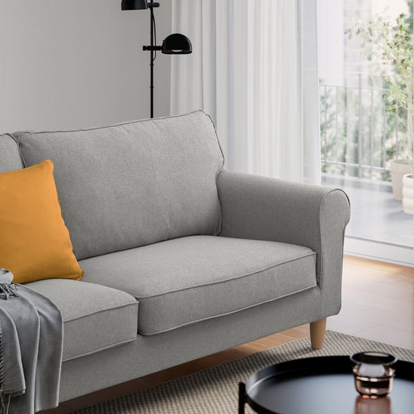 Modern living room with light grey GÄLLTOFTA loveseat, black lamp, and small table.