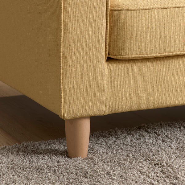 Modern couch in mustard yellow fabric with clean lines and wooden legs on fluffy white carpet.