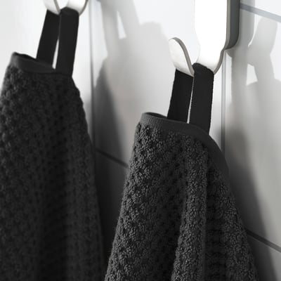 Two towels hang: one soft beige, one textured black. Absorbent and durable.