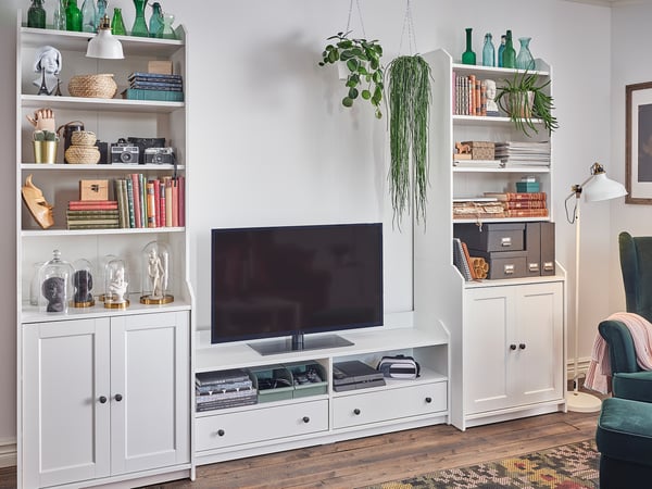 Modern living room with HAUGA white cabinet, tv, books, decor, plants.