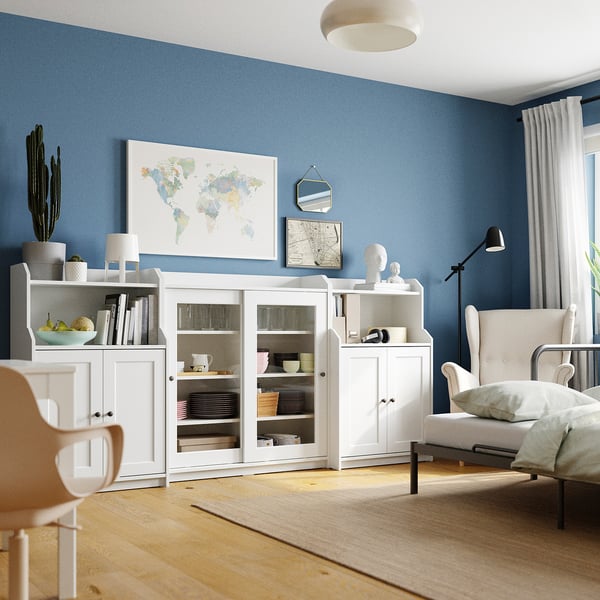 Bright living room with blue walls, white furniture, and a global map poster. A cosy chair with a floor lamp and wooden floor.