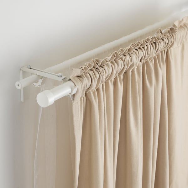 Adjustable white curtain rod with beige curtains.