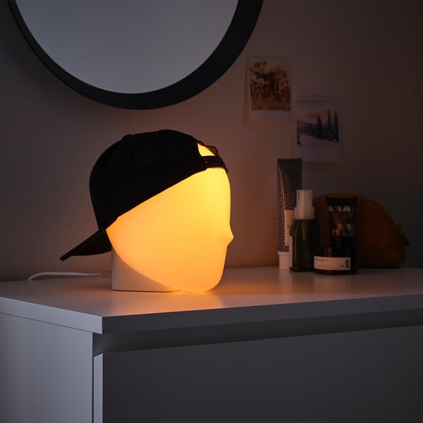 ISKÄRNA lamp shaped like a black baseball cap with yellow light