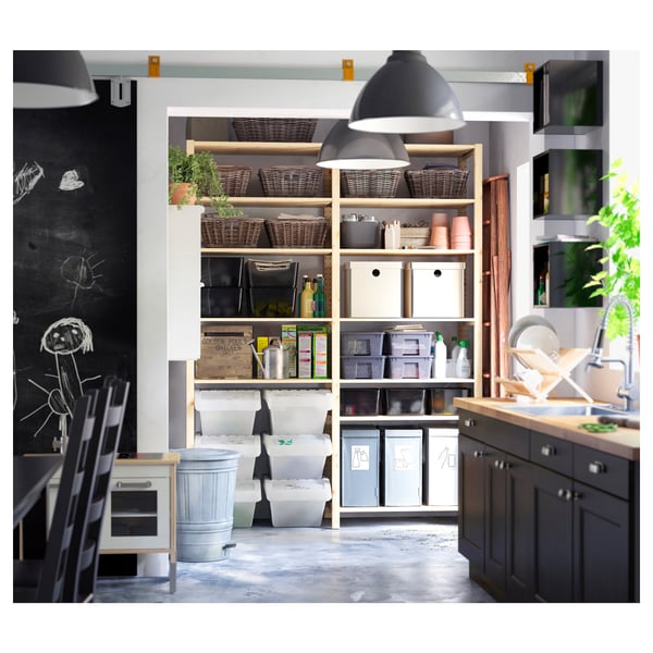 Modern kitchen with IVAR shelves, baskets, and bins in light wood, hanging black lamps, and a chalkboard wall.