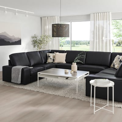 Modern living room with large black l-shaped KIVIK sofa, white coffee table, and large window, offering a cosy and stylish space.