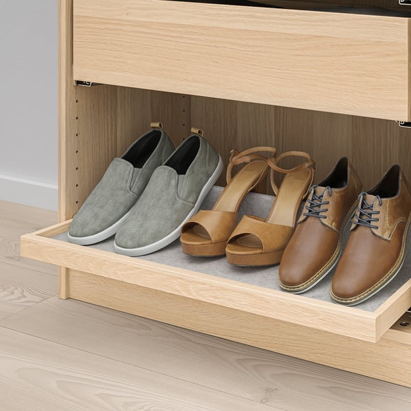 Pull-out wooden tray in light-colored closet holds three pairs of shoes, making them easily accessible and organised in a tidy wardrobe.
