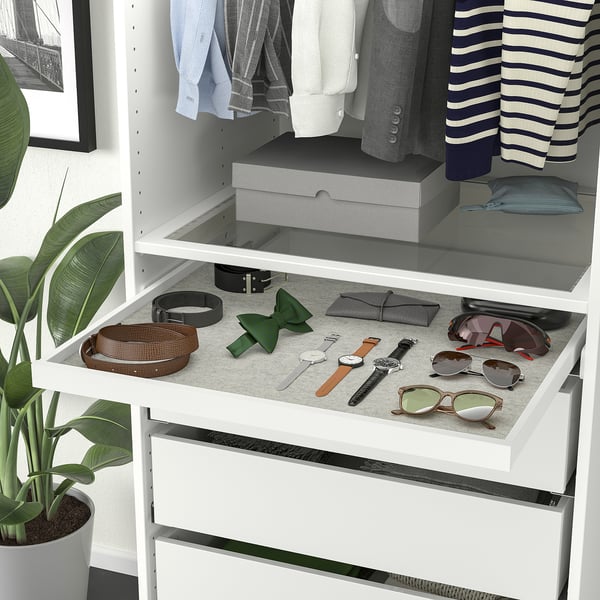 Wardrobe organiser with drawer for accessories, upper shelves with clothes and plant beside.