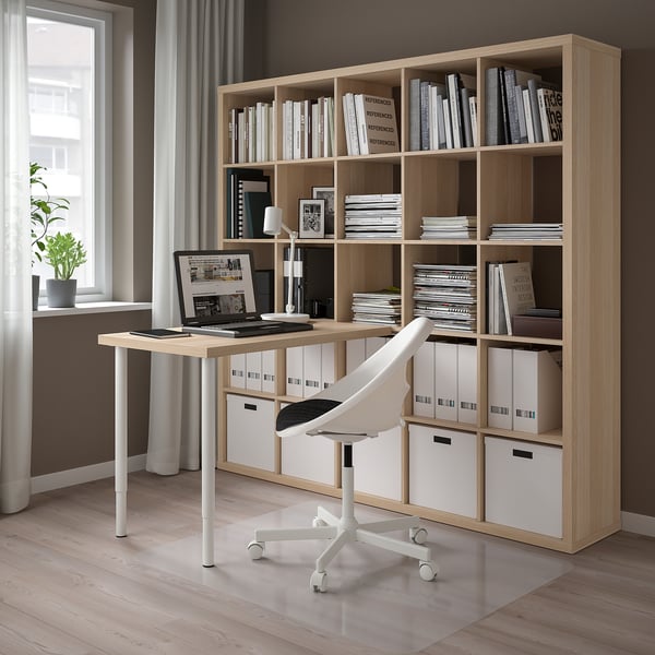 Home office with LINNMON desk, chair, laptop, lamp, and large bookcase with books and boxes.