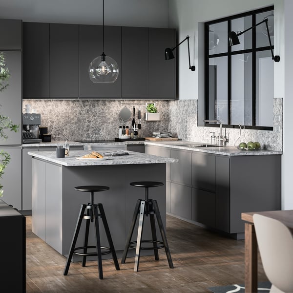 Modern kitchen with MITTLED black pendant lights, grey cabinets, marble countertop, and two high stools.
