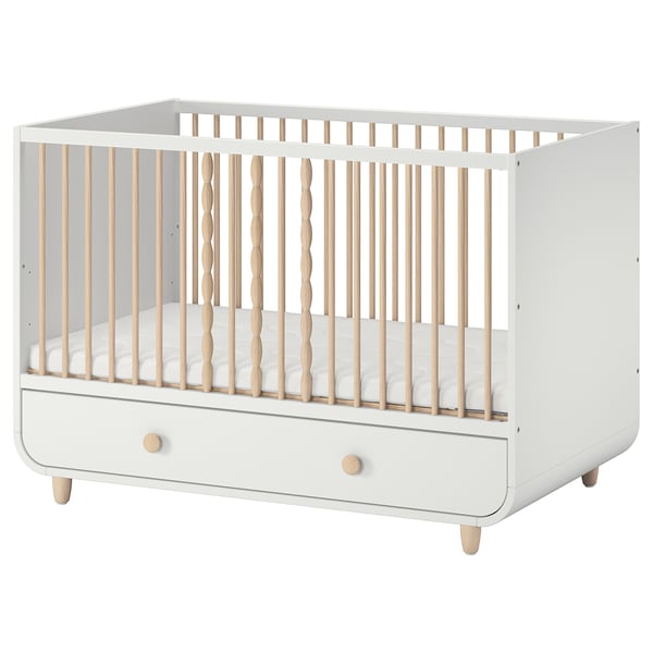 A white MYLLRA baby crib with natural wood accents, including adjustable sides and a bottom drawer for storage.
