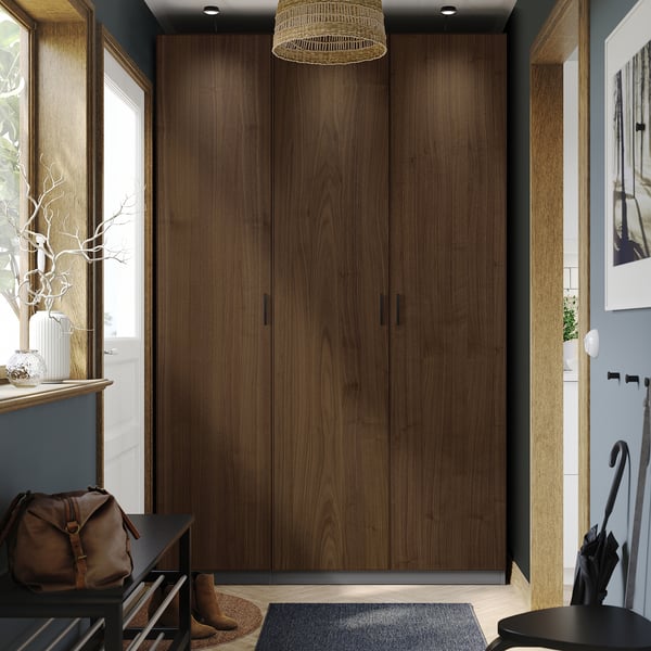Modern entryway with tall walnut PAX wardrobe, leather bag, vases, and umbrella stand.