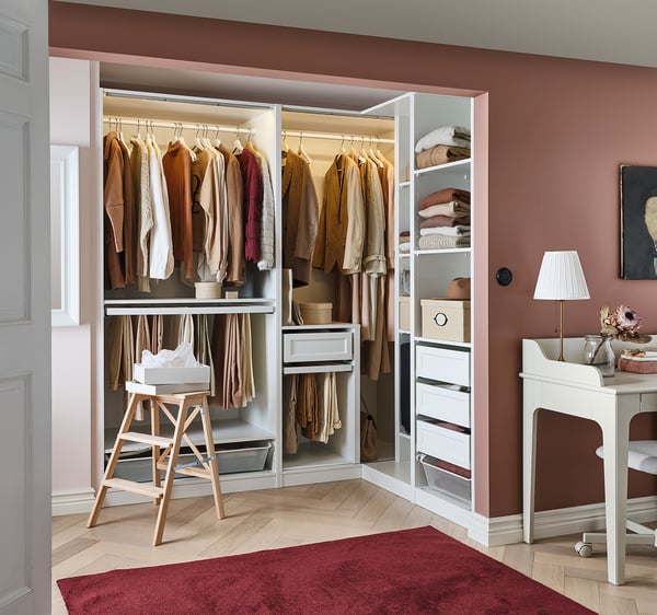 Modern walk-in closet with white PAX storage, red rug on wood floor.