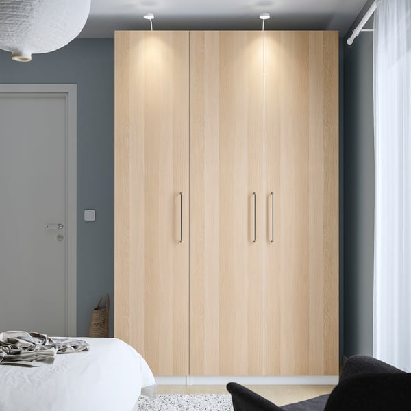 Wooden PAX wardrobe centred against grey wall, taller than bed.