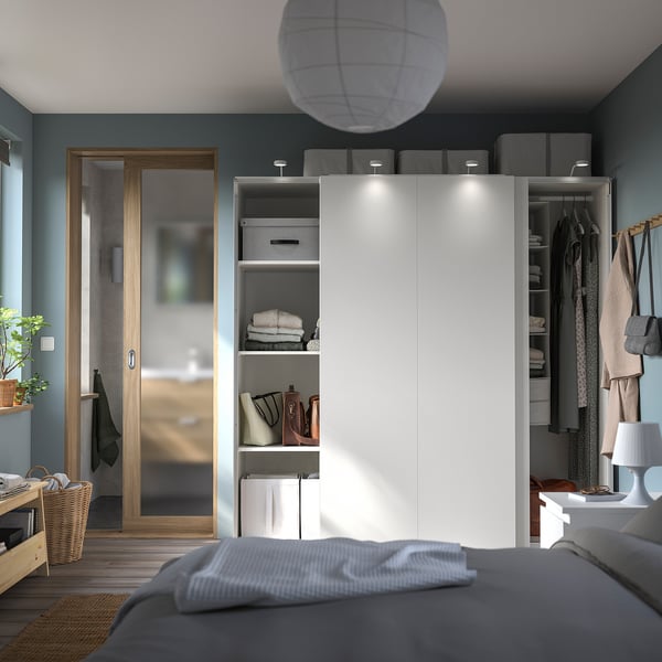 Modern bedroom with white PAX wardrobe, sliding doors, grey bed, wooden flooring, blue-green walls, and hanging decorations.