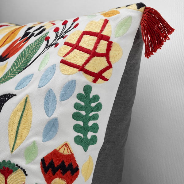 Colourful embroidered pillow with leaf patterns and red tassel, showcasing intricate design and high-quality artisanship.