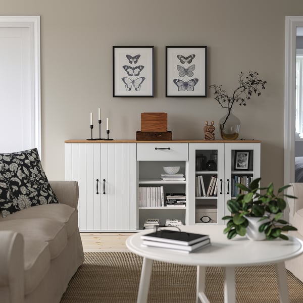 Modern living room with SKRUVBY sideboard, butterfly prints, beige sofa, and round coffee table with books and plant.