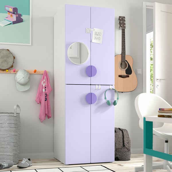 A kids bedroom featuring a tall lavender SMÅSTAD wardrobe with mirrored doors. It stands between a guitar and a desk, larger than nearby items.
