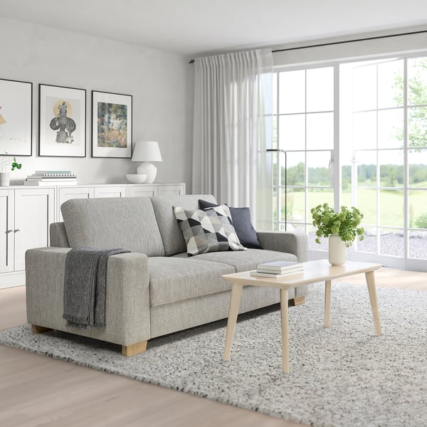 Modern living room with SÖRVALLEN sofa, coffee table, books, and greenery under large windows.