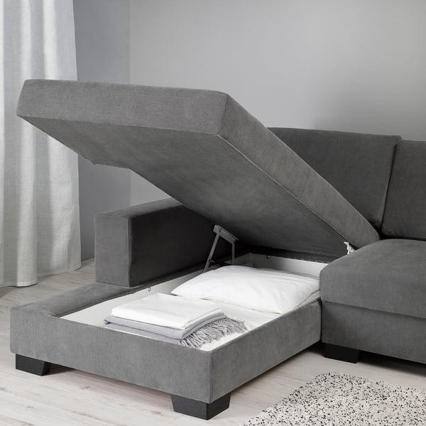 Modern grey sofa with extendable bed function, showcasing storage and comfort, ideal for small spaces.