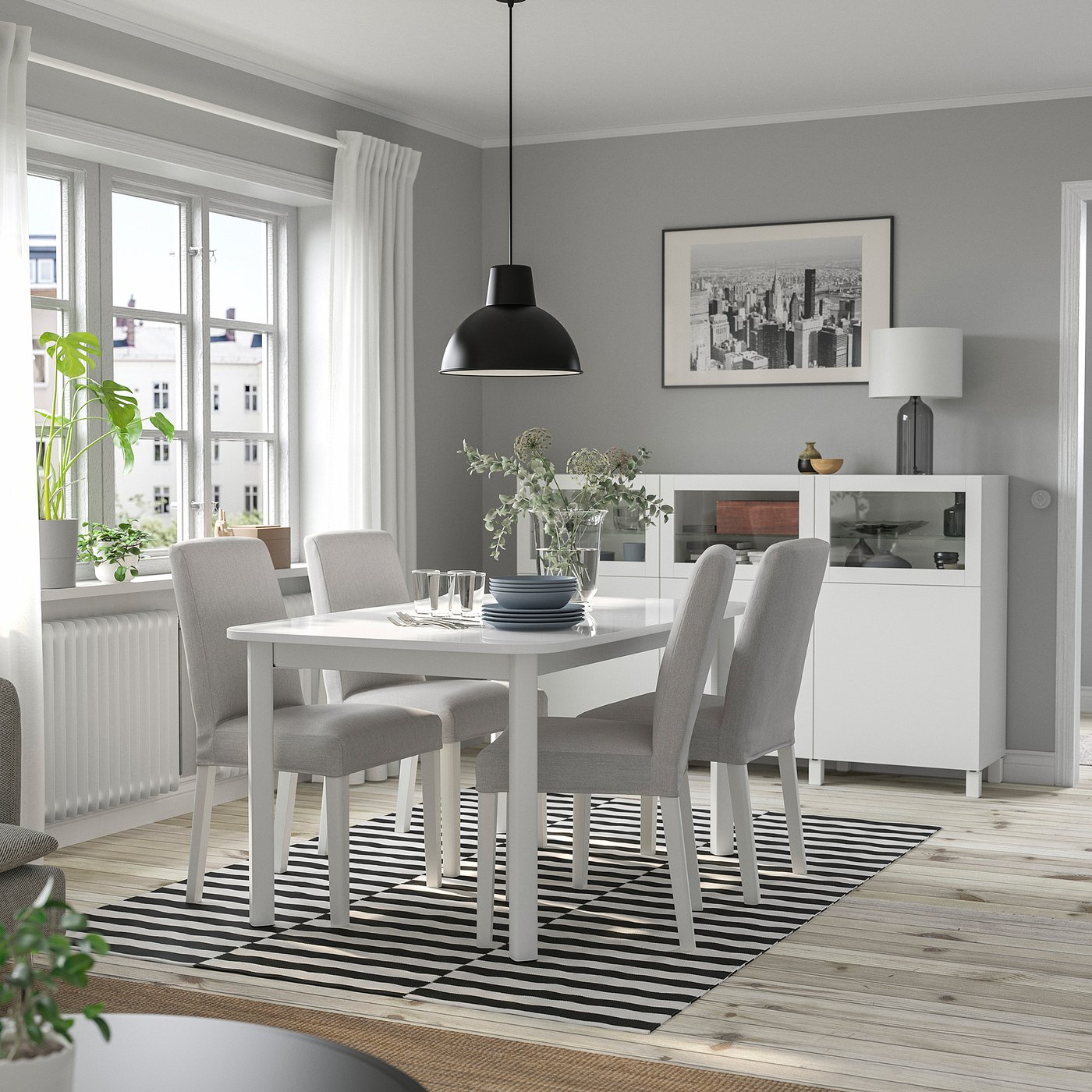 STRANDTORP white extendable dining table with grey chairs, stripe rug, black pendant light, framed city print, large window, soft lighting.