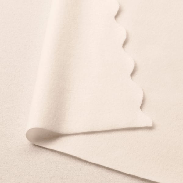 Soft, off-white fleece throw made from eco-friendly recycled polyester, draped elegantly.
