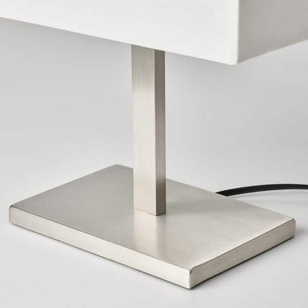 Modern metallic table lamp with sleek, rectangular shade, sturdy base.