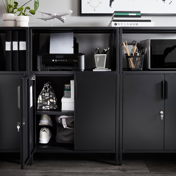 Black metal storage unit with open shelves holding office supplies, printer, and a closed cabinet with keys.