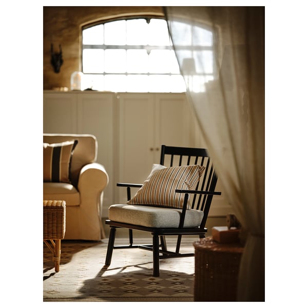 Cosy living room with rocking chair, sofa, wool rug, wicker chair, and sheer curtains.