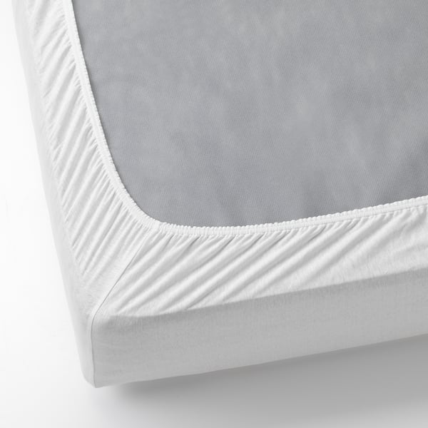 White fitted sheet on mattress, elastic corners ensure snug fit.