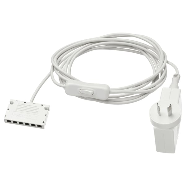 A white ANSLUTA power adapter with a cable and plug. Its made of polycarbonate plastic and designed to control up to 6 light sources with one switch.