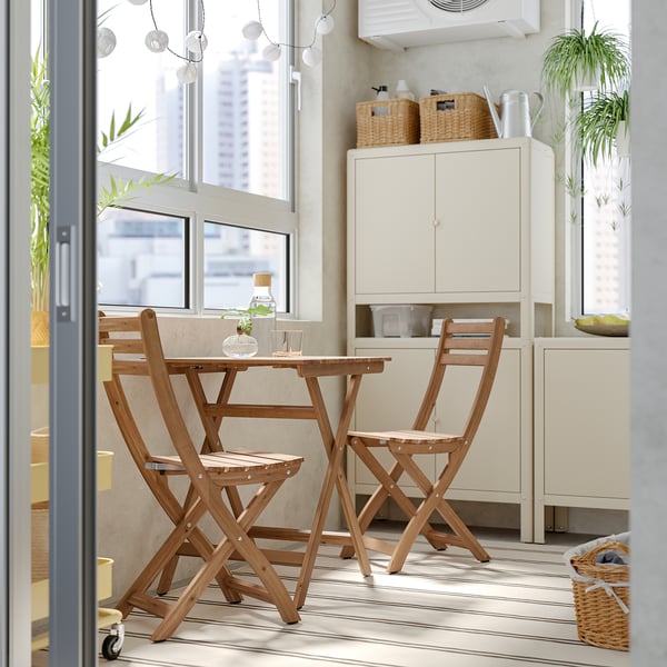 ASKHOLMEN folding outdoor dining set with table & 2 chairs, cushions, near window.