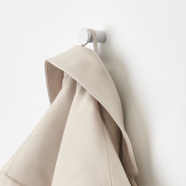 Beige towel on white hook, wall storage solution.