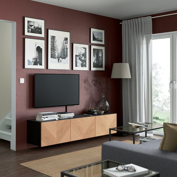 Modern living room with BESTÅ tv bench, books, vase, & photos. Grey sofa & floor lamp; cosy ambiance.