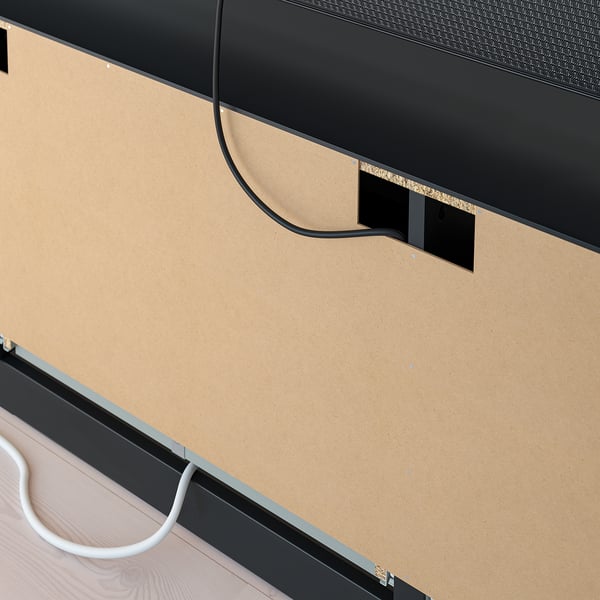 Black tv bench with cork top, cable management holes visible, drawers for storage, wall anchor required.