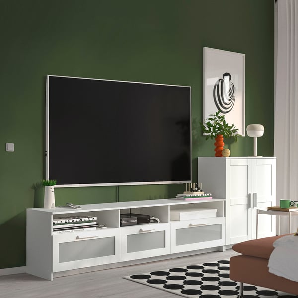 Modern living room with green walls, BRIMNES tv unit, orange chair, black & white rug.