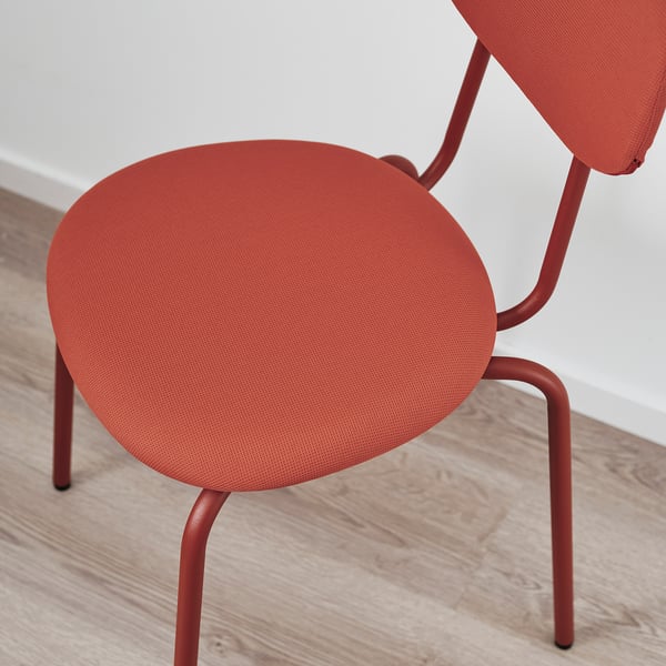 Bright red upholstered chair with modern design and metal legs, positioned on a wooden floor.