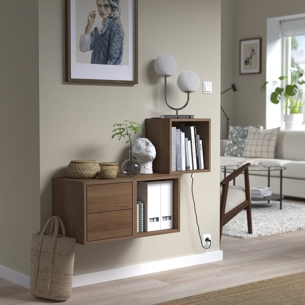 Modern living room with wall-mounted EKET shelves, decorative items, and unique light fixture.